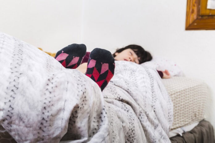 meisje-die-kleurrijke-sokken-dragen-terwijl-het-dutten-op-bed beste warmtedeken