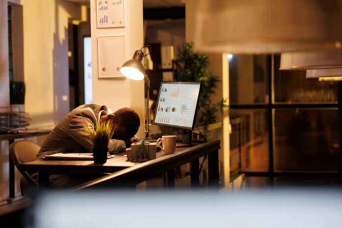 Tired drained entrepreneur sleeping on desk in startup office Burn-out voorkomen