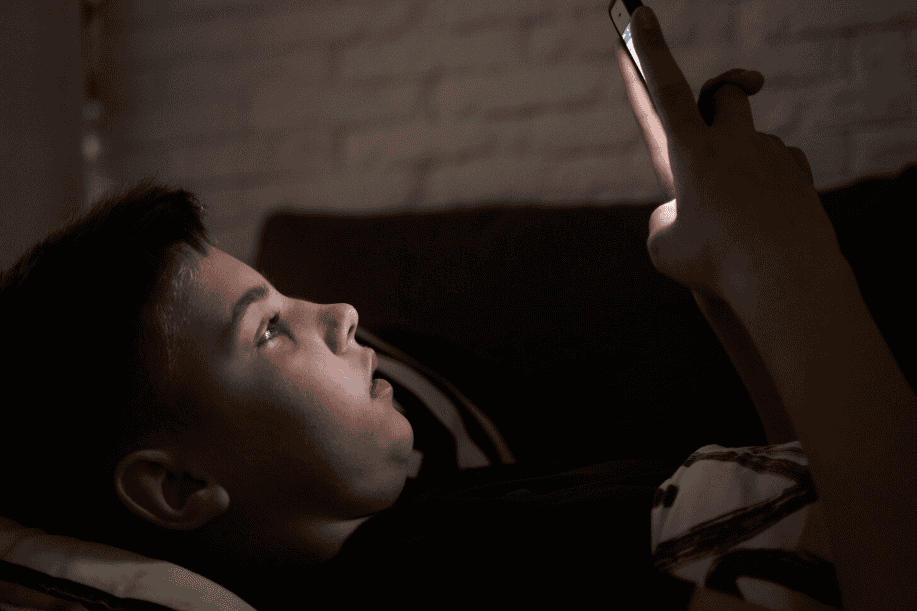 kind ligt in bed met een schermverslaving